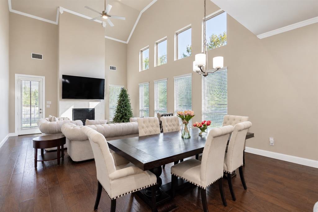 Vaulted ceiling with crown molding, elevated windows, wood-finish flooring, fireplace with a mantle, and recessed lighting