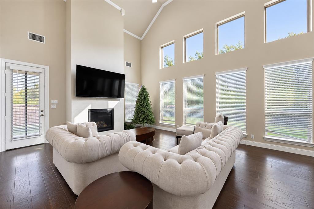 Vaulted ceilings, dark wood-finish flooring, a fireplace, and multiple windows with blinds