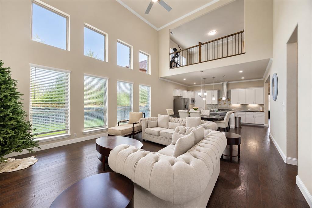 Two-story living area featuring dark wood-finish flooring, high ceilings, and multiple windows with blinds