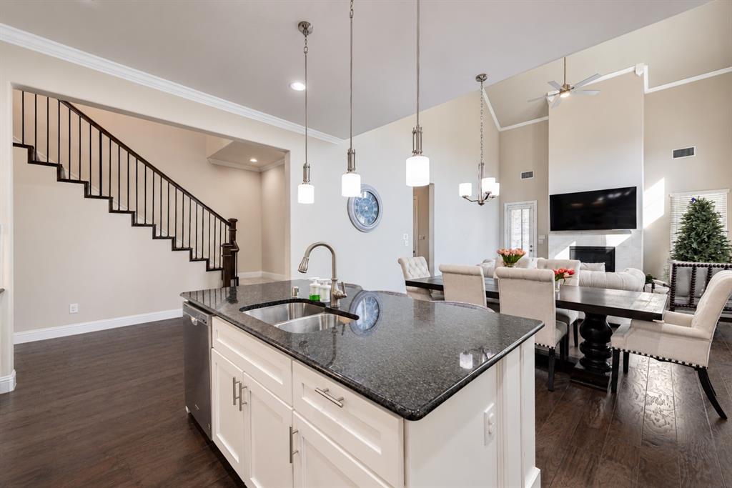 Kitchen island with dark countertop, stainless steel sink, and pendant lighting