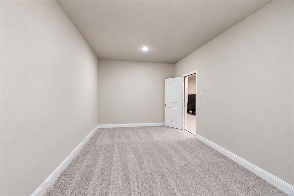 Recessed ceiling lighting, light gray wall paint, gray patterned carpeting, white trim, and a white interior door