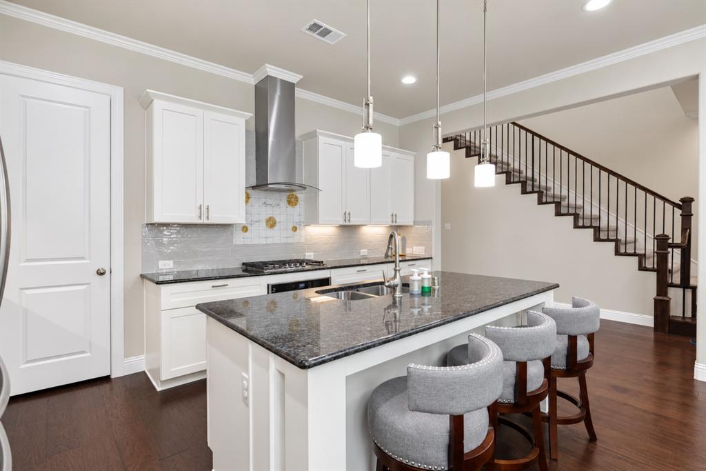 Kitchen with white cabinetry, dark stone countertops, and a full tile backsplash