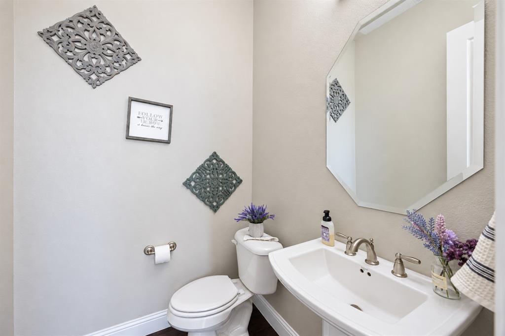 Pedestal sink with brushed nickel faucet, octagonal wall mirror, and neutral wall paint
