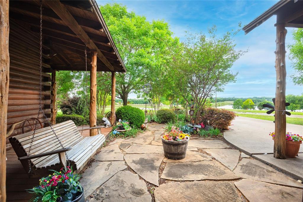Log exterior with covered porch featuring natural log support posts and irregular flagstone paving