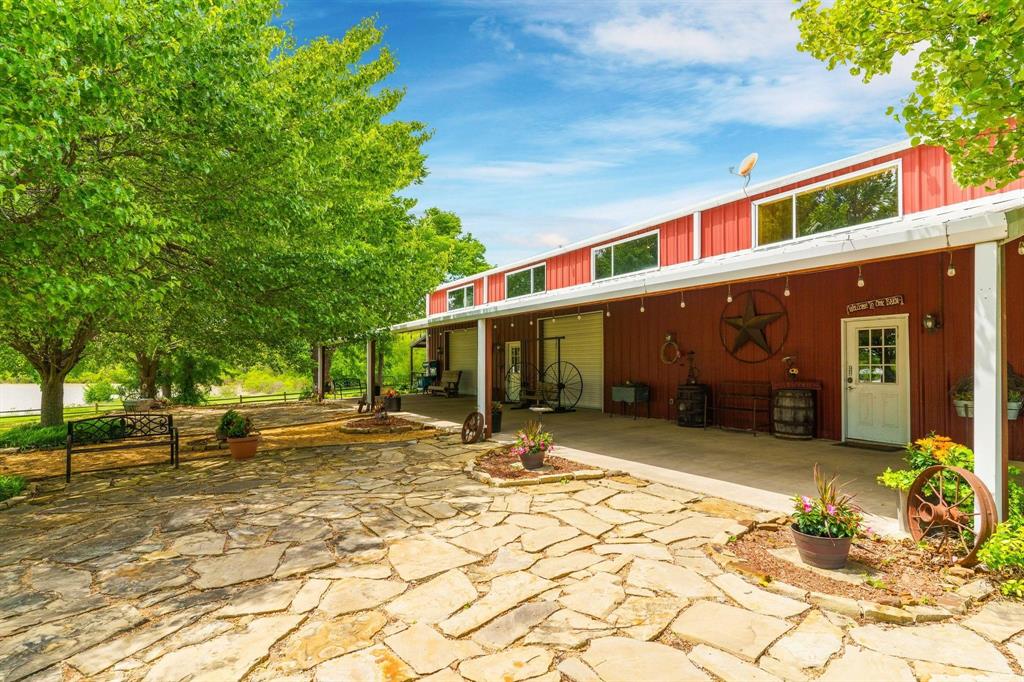 Exterior featuring a red metal siding structure with a concrete patio, stone hardscaping, and a covered porch area
