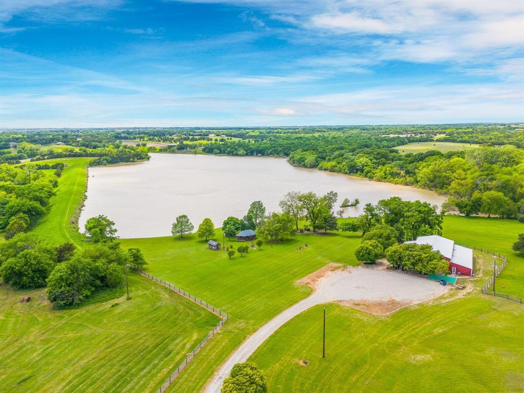 Expansive acreage featuring private waterfront access, open pasture land, mature trees, and a multi-purpose barn structure