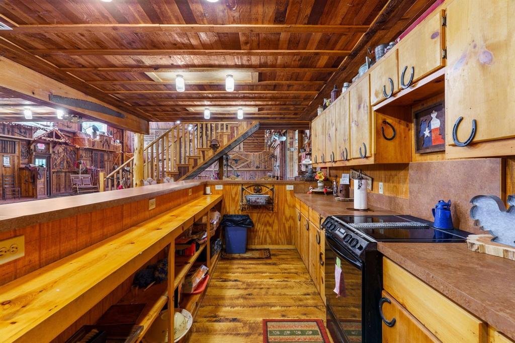 Kitchen featuring tongue-and-groove wood plank ceiling, custom natural wood cabinetry, wood-finish flooring, integrated breakfast bar, and rustic metal hardware