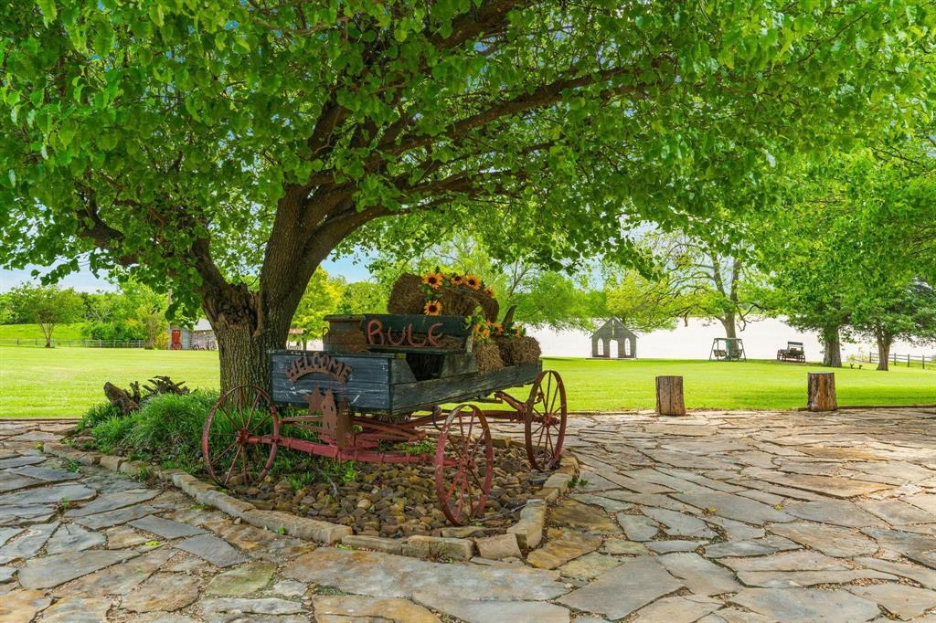 Expansive grounds featuring a natural stone patio, mature shade trees, and open lawn space