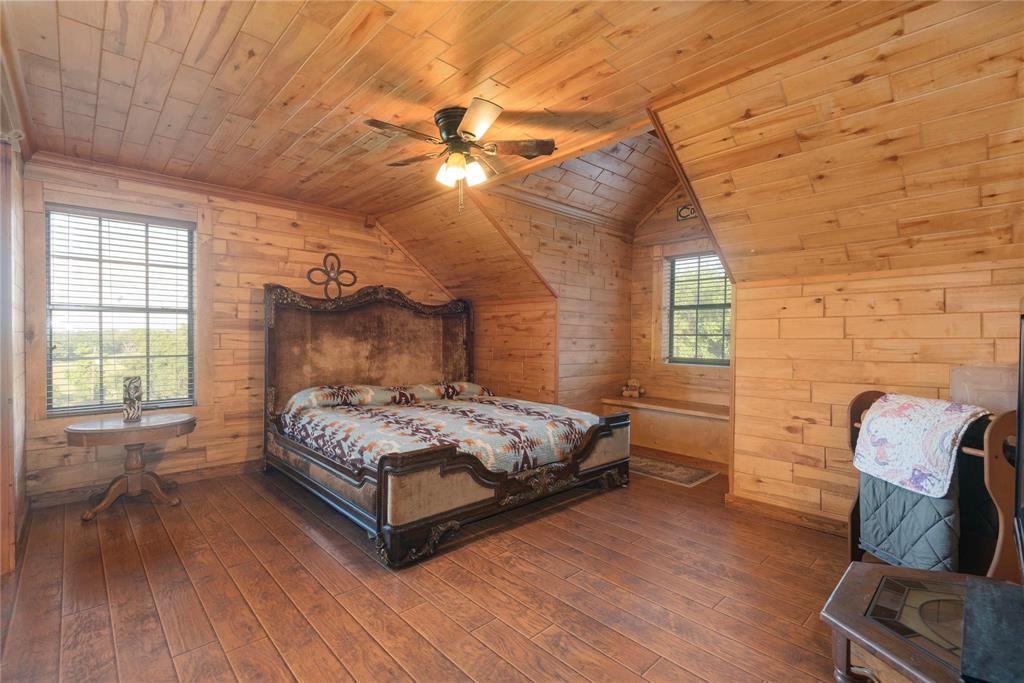 Wood-planked walls and vaulted ceilings featuring exposed wood-finish paneling, wood-finish flooring, and a central ceiling fan with integrated light fixture