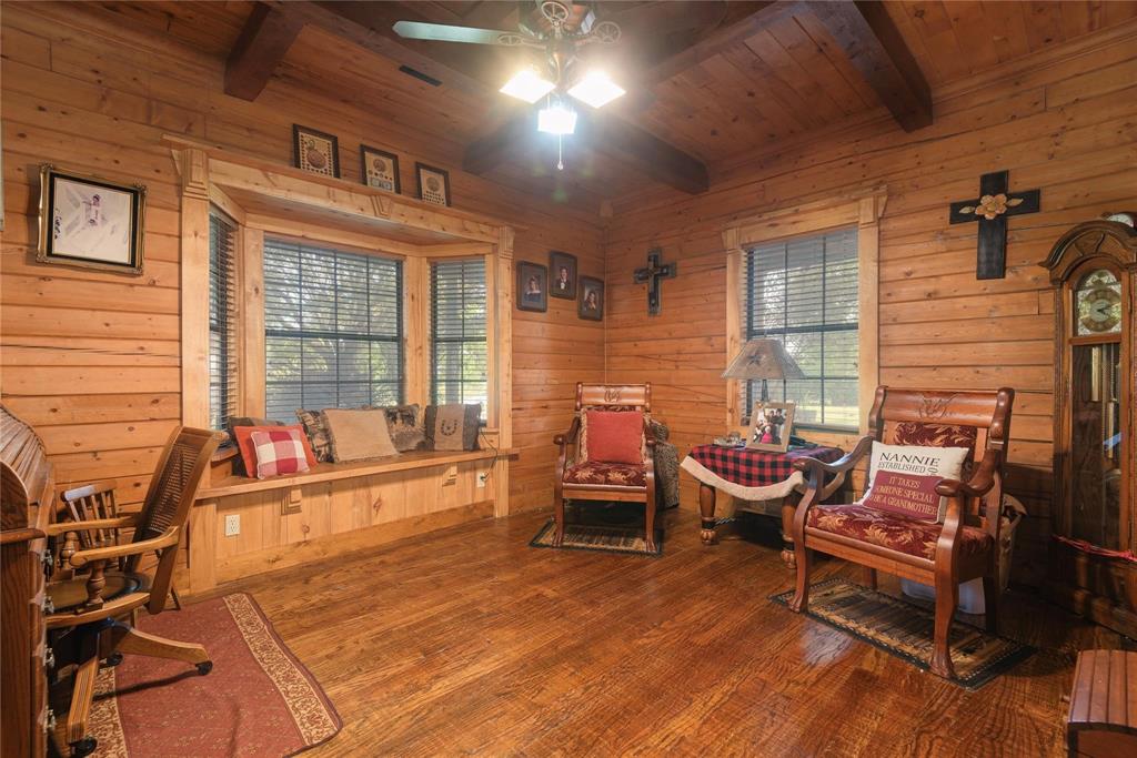 Natural log walls, exposed timber ceiling beams, hardwood flooring, and a built-in window seat with decorative wood trim