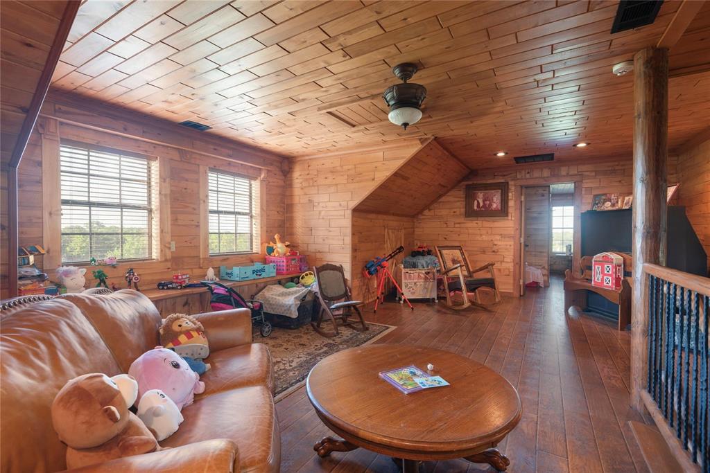 Interior space featuring natural wood wall paneling, plank wood-finish flooring, a vaulted plank-paneled ceiling, and a prominent wood support column