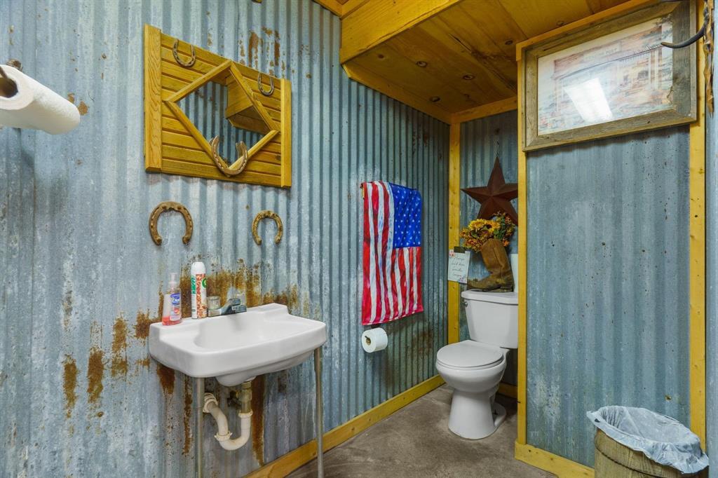 Corrugated metal wall paneling with exposed wood framing, wall-mounted porcelain basin, and concrete flooring