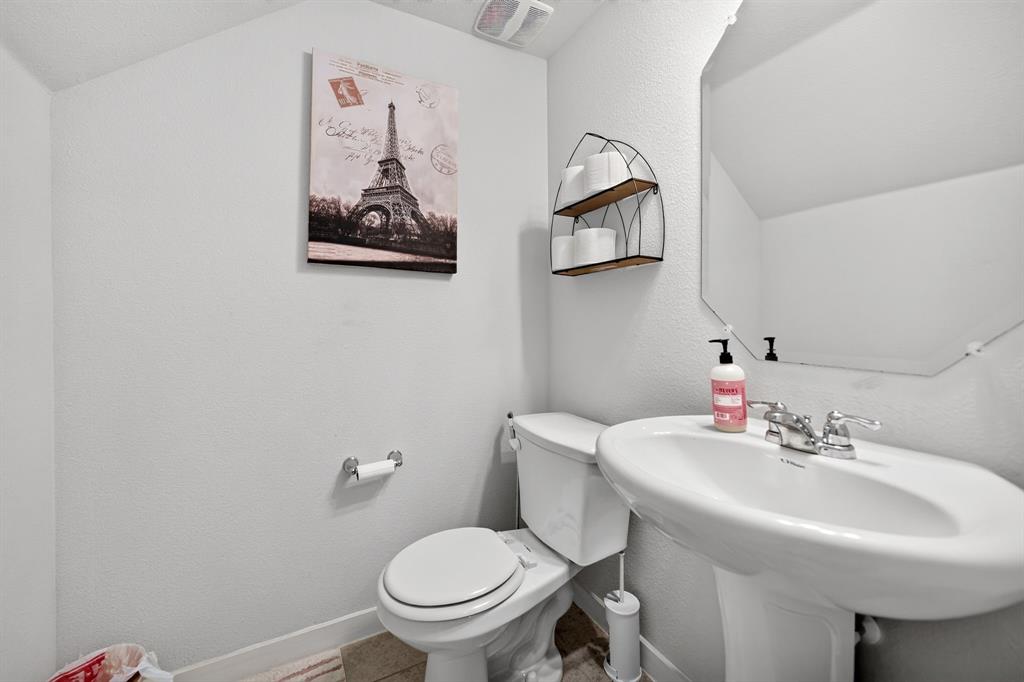 Pedestal sink with chrome faucet, toilet, wall-mounted mirror, and wall shelving