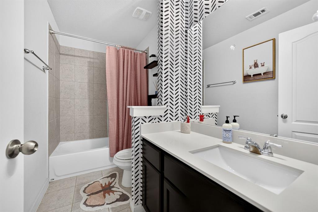 Bathroom featuring a vanity with an integrated sink, polished chrome faucet, full-width mirror, and a tiled tub/shower combination