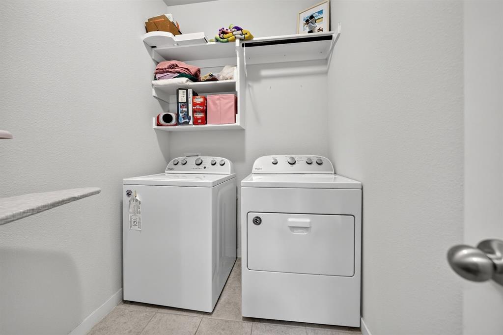 Dedicated laundry room featuring side-by-side white appliances, including a top-load washer and electric dryer