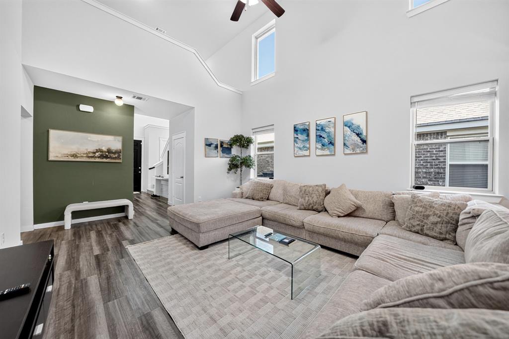 Vaulted ceilings featuring a ceiling fan, wood-finish flooring, and multiple windows