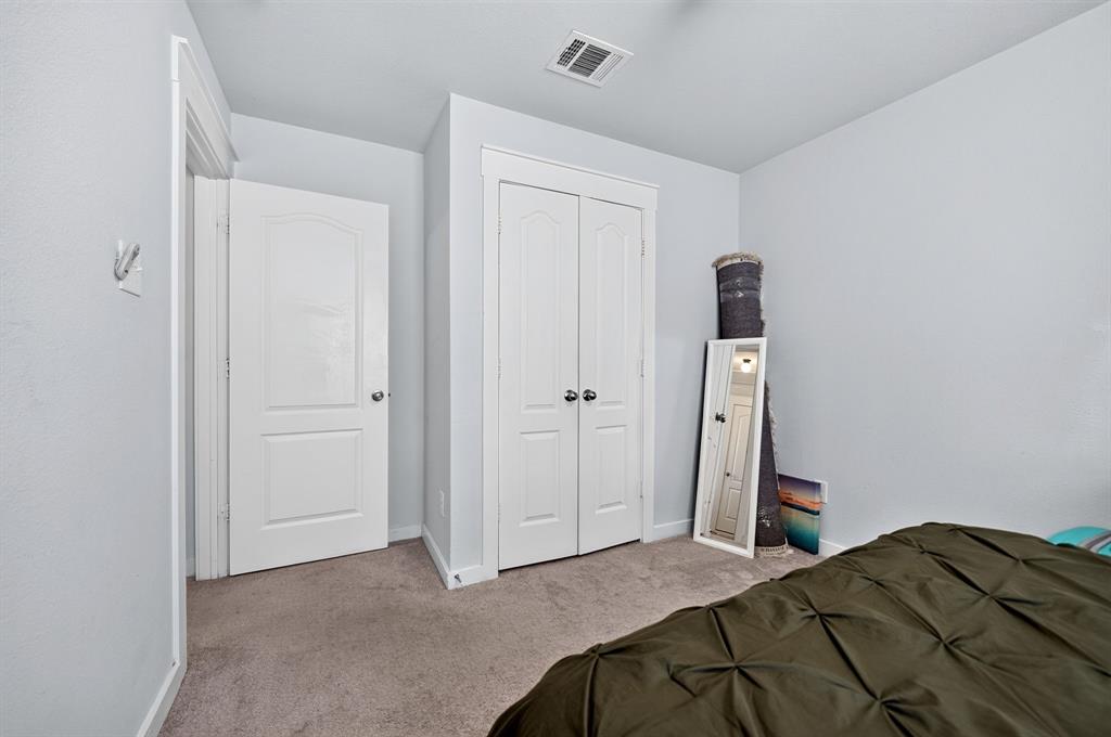 Spacious secondary bedroom with neutral wall finishes, carpet flooring, and dual closet doors providing ample storage