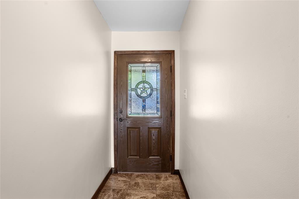 Wood-finish entry door with decorative glass inlay, durable tile flooring, and neutral wall finishes