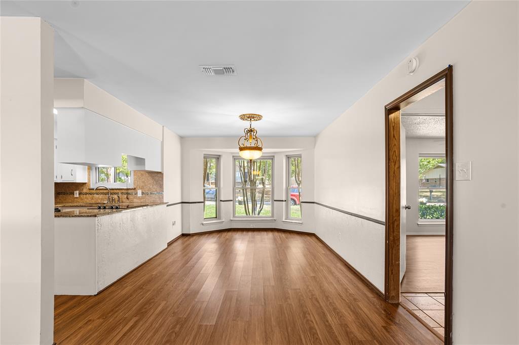 Wood-finish flooring, bay window, built-in lighting fixture, kitchen pass-through, and white cabinetry