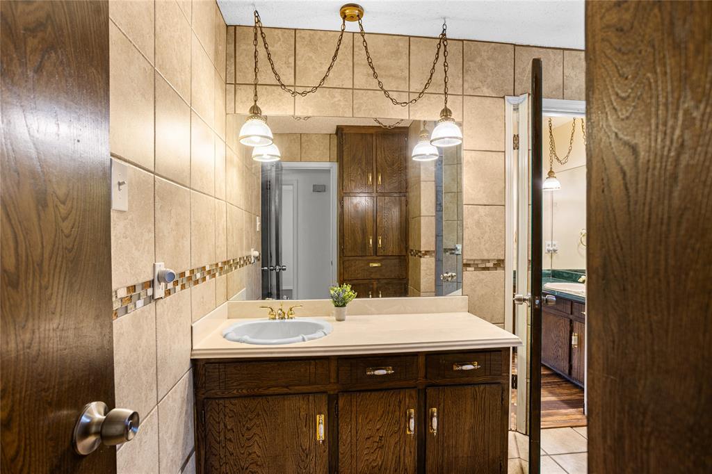 Wood-finish vanity with a recessed sink and single-handle faucet, complemented by a large wall-mounted mirror