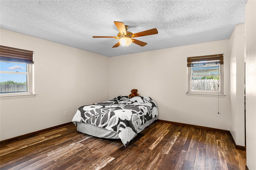 Wood-finish flooring, two windows with blinds, ceiling fan with integrated lighting, and neutral wall paint