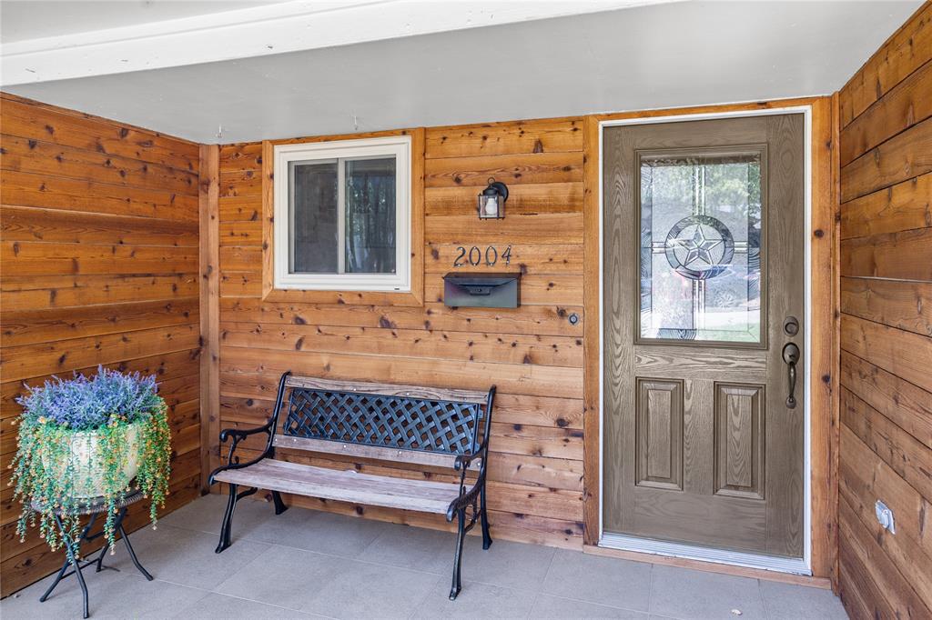 Wood-paneled entryway featuring a gray panel door with decorative glass, a porch light fixture, and a front window