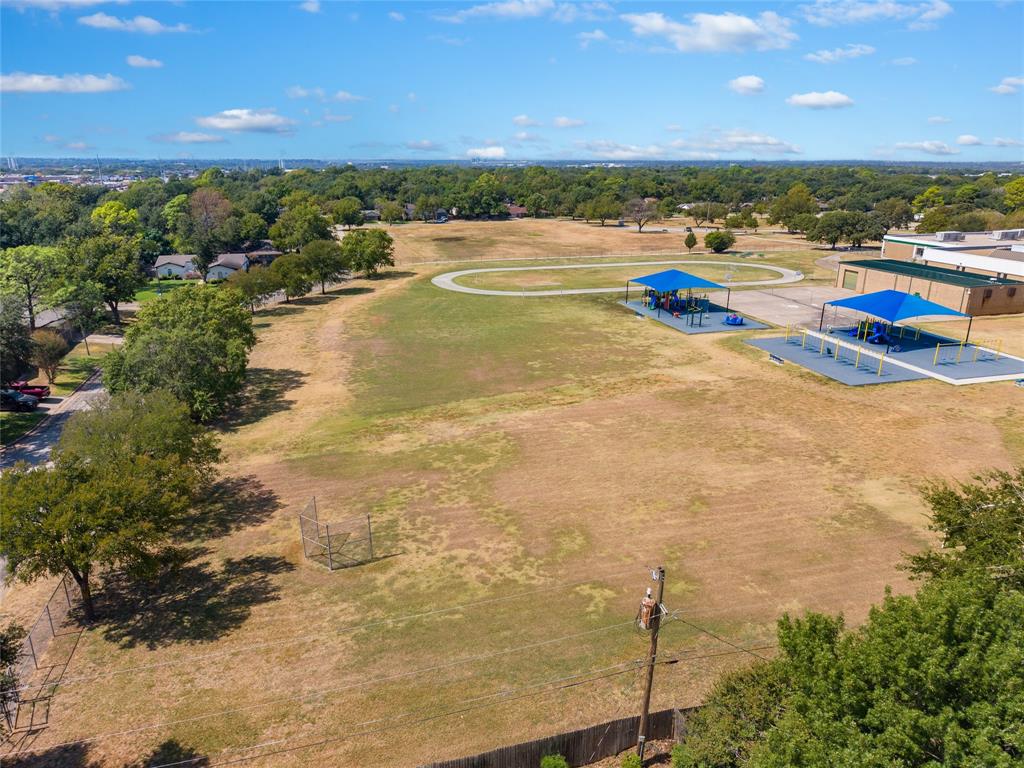 Expansive grounds featuring a running track, two shaded play structures, and surrounding mature trees