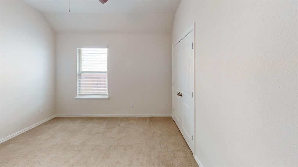 Carpeted room featuring a single window with blinds, a white door with brass hardware, a ceiling fan, and textured walls Carpeted room featuring a single window with blinds, a white door with brass hardware, a ceiling fan, and textured walls