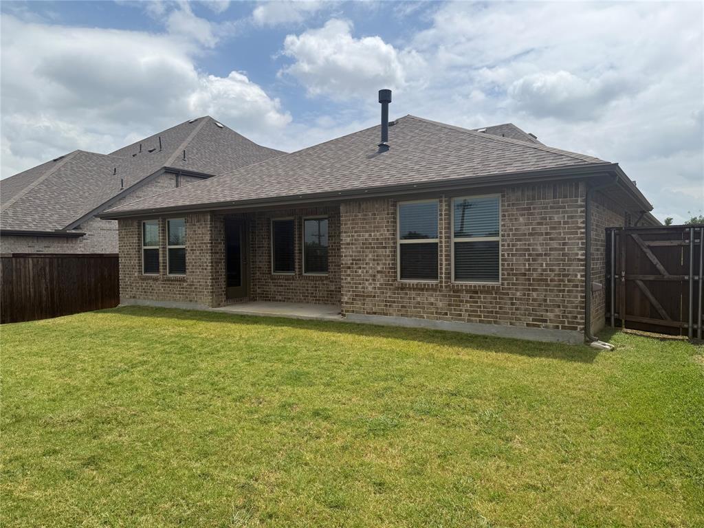 Brick exterior with a covered patio, fenced yard, and composition shingle roof