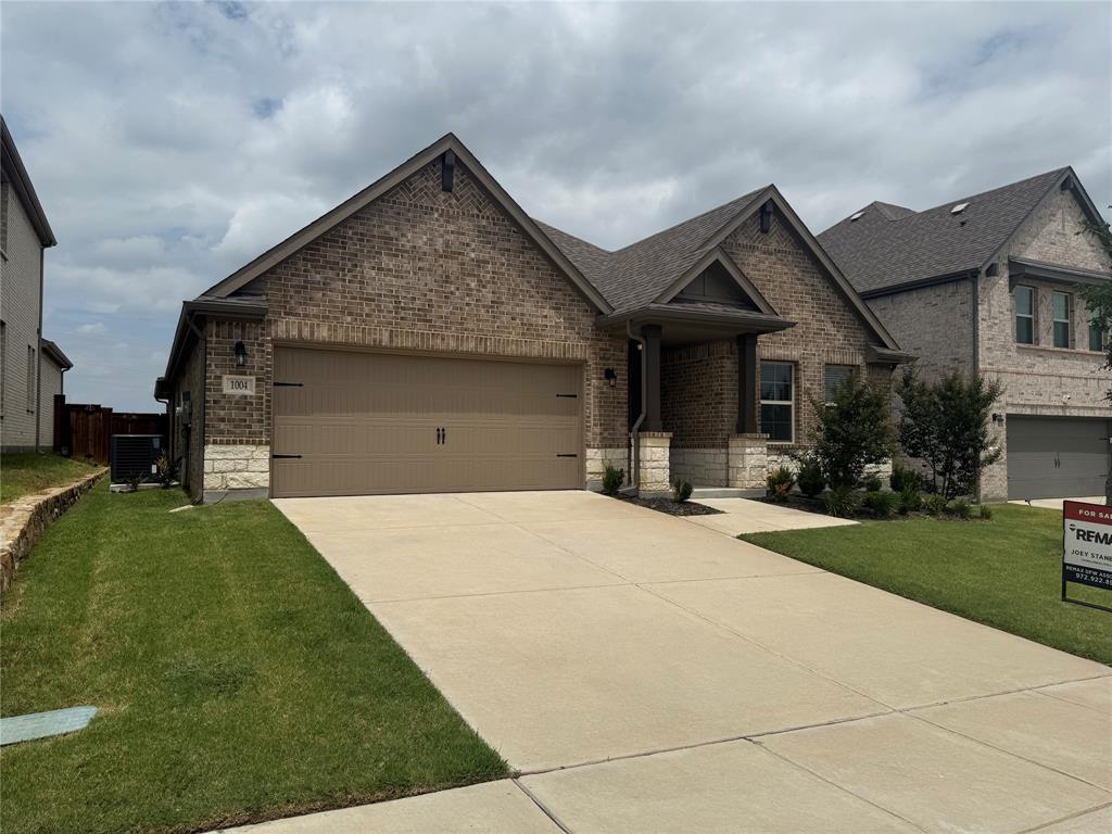 Brick Colonial home featuring a two-car attached garage, concrete driveway, and manicured front lawn with established landscaping Brick Colonial home featuring a two-car attached garage, concrete driveway, and manicured front lawn with established landscaping