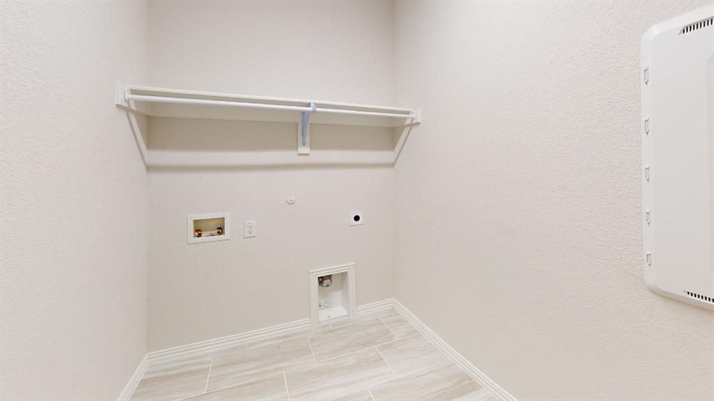 Utility area featuring tile flooring, a built-in shelf, and a clothing rod