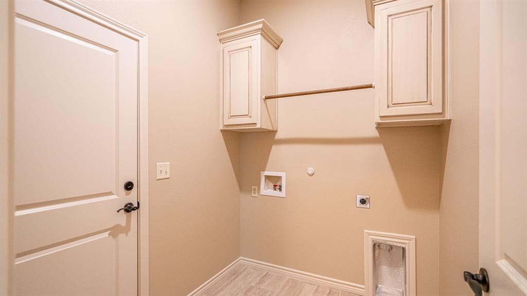 Full sized laundry room with washer and dryer hook ups, cabinets and drying rod