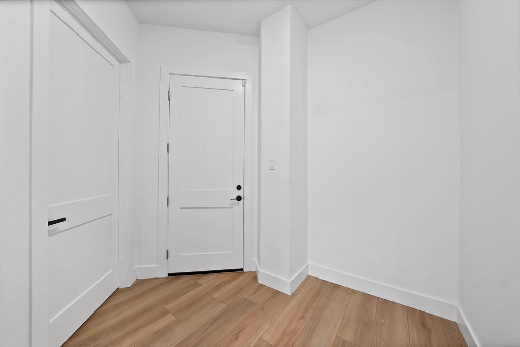 Light wood-finish flooring, white paneled doors, and white walls