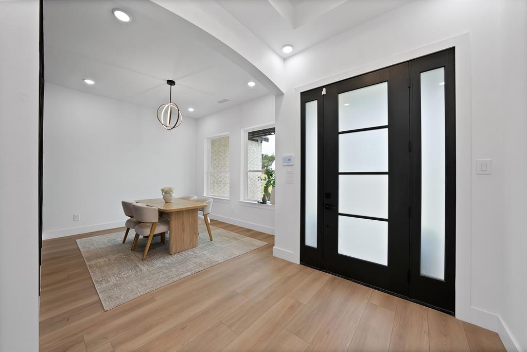 Wide plank wood-finish flooring, recessed lighting, and a modern chandelier Wide plank wood-finish flooring, recessed lighting, and a modern chandelier