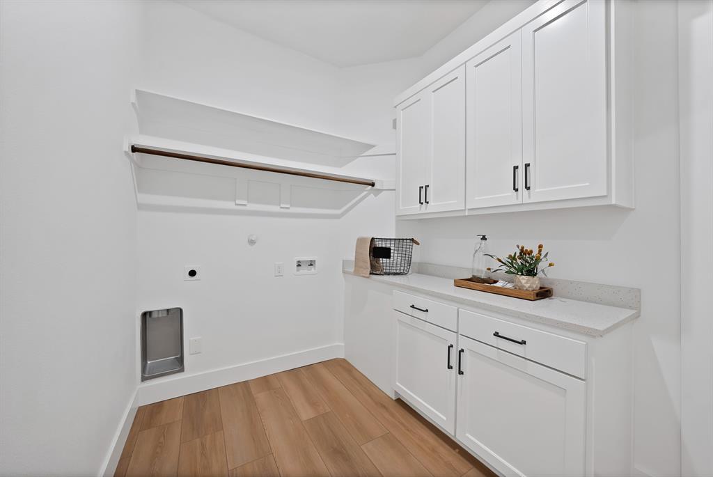 White cabinetry, wood-finish flooring, light-toned countertop, and built-in shelving with a hanging rod