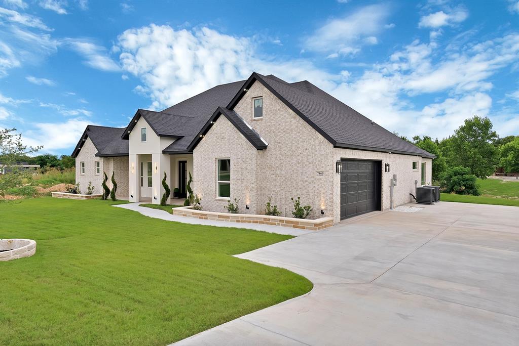 Light brick exterior with contrasting dark roof, attached two-car garage, concrete driveway, and manicured lawn Light brick exterior with contrasting dark roof, attached two-car garage, concrete driveway, and manicured lawn