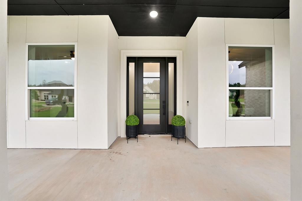 Covered front porch with a dark ceiling accent, vertical white paneling, and a full-light entry door Covered front porch with a dark ceiling accent, vertical white paneling, and a full-light entry door