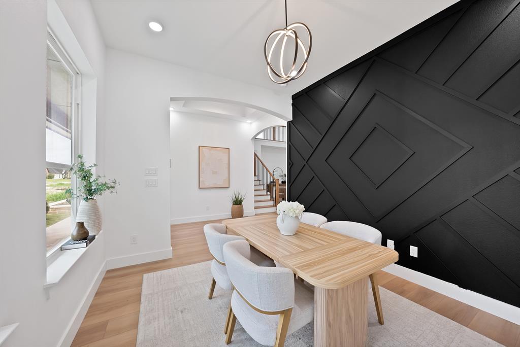 Recessed lighting, wood-finish flooring, and a decorative accent wall with geometric paneling Recessed lighting, wood-finish flooring, and a decorative accent wall with geometric paneling