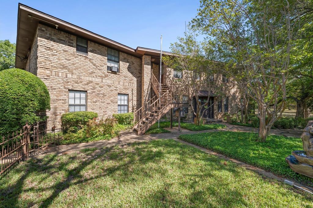 Brick exterior construction, multiple windows, exterior staircase, landscaped grounds, and a decorative water feature