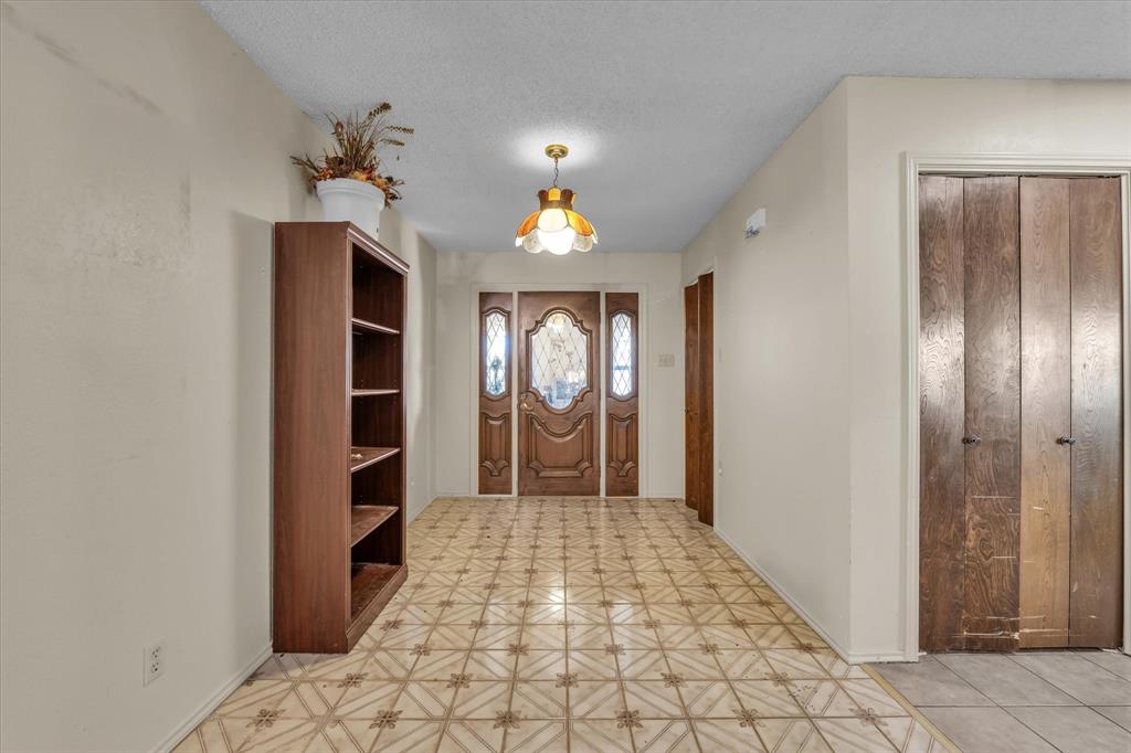 Patterned tile flooring, wood-paneled entry doors with decorative glass inserts, and a ceiling-mounted light fixture