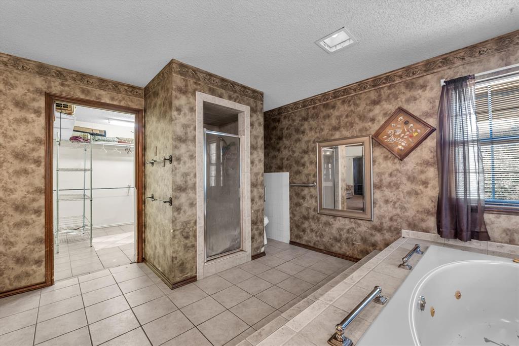 Tile flooring, glass-enclosed shower, built-in bathtub, window with blinds, and recessed lighting