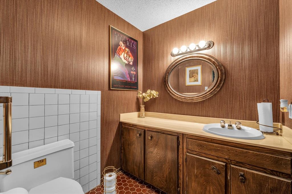 Vanity with wood-finish cabinetry, a built-in sink, and an oval mirror