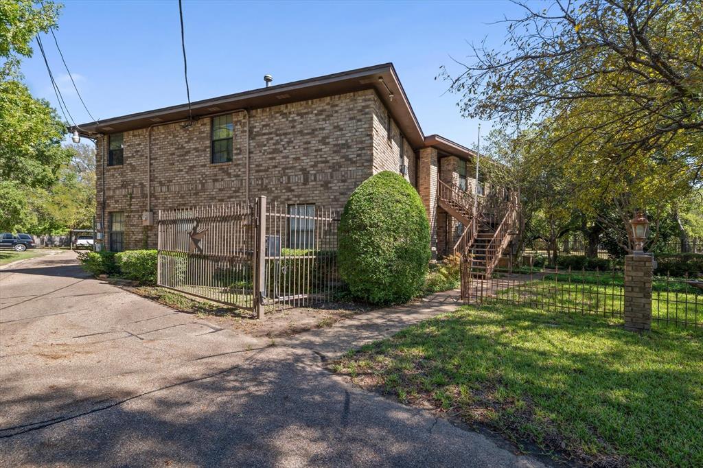 Brick exterior with multiple windows, featuring a wrought iron fence with a decorative gate