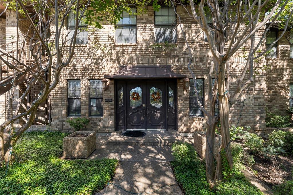 Brick facade with multiple windows, a covered double entry door, and concrete walkways