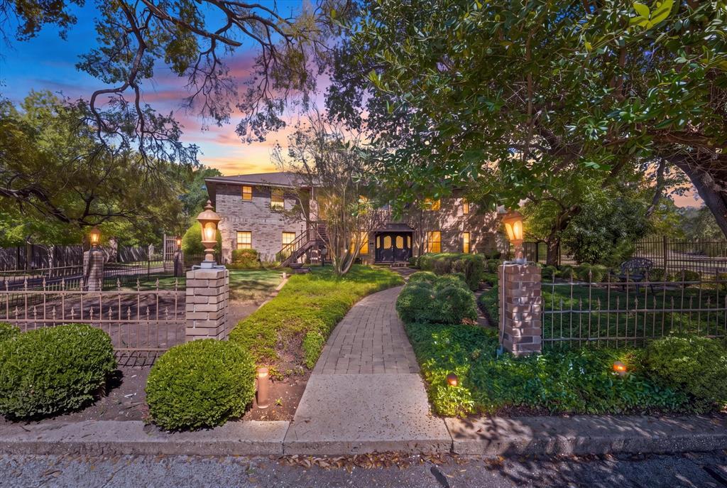 Stone exterior, brick paver walkway, extensive landscaping, decorative metal fencing, and exterior lighting fixtures Stone exterior, brick paver walkway, extensive landscaping, decorative metal fencing, and exterior lighting fixtures