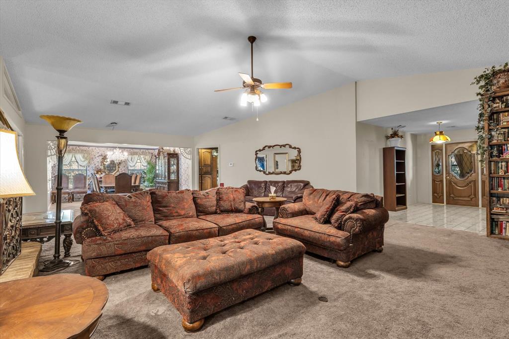 Carpeted living area with a vaulted ceiling, ceiling fan, and recessed lighting