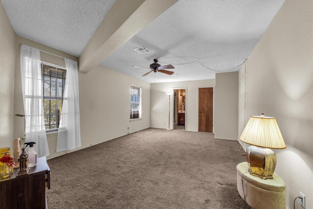 Neutral wall finishes, textured ceiling, brown carpet flooring, and a ceiling fan with light