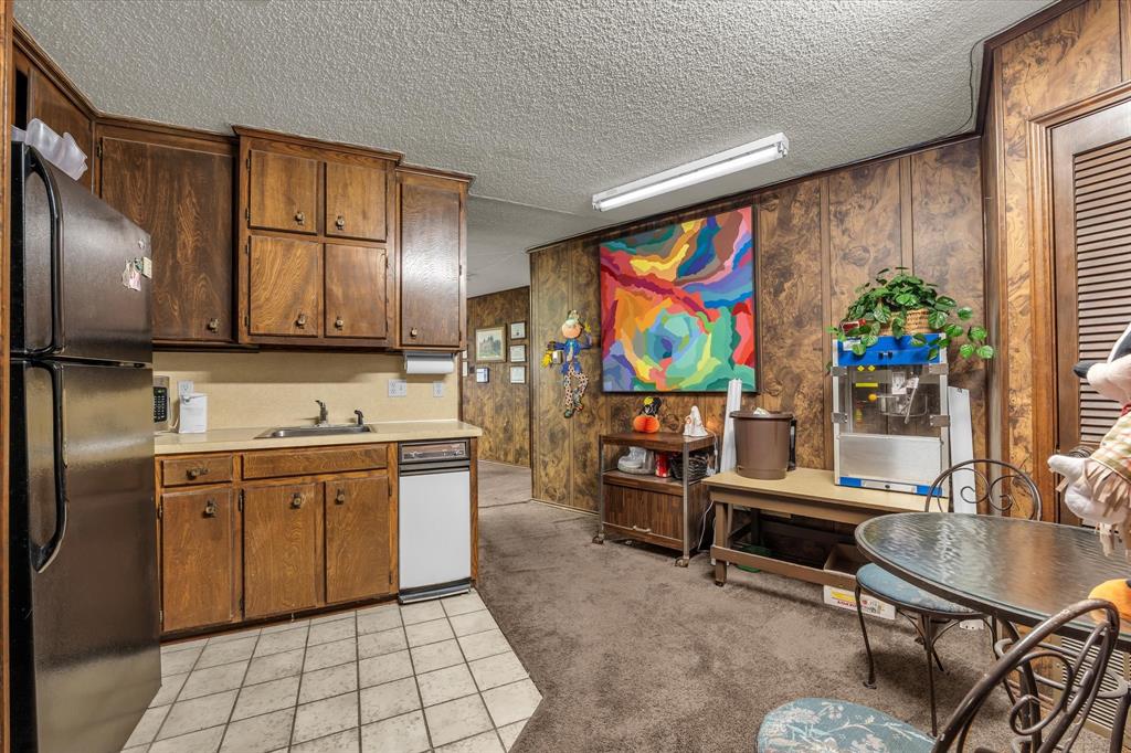 Kitchen featuring wood cabinetry, a stainless steel refrigerator, a white dishwasher, and tiled flooring