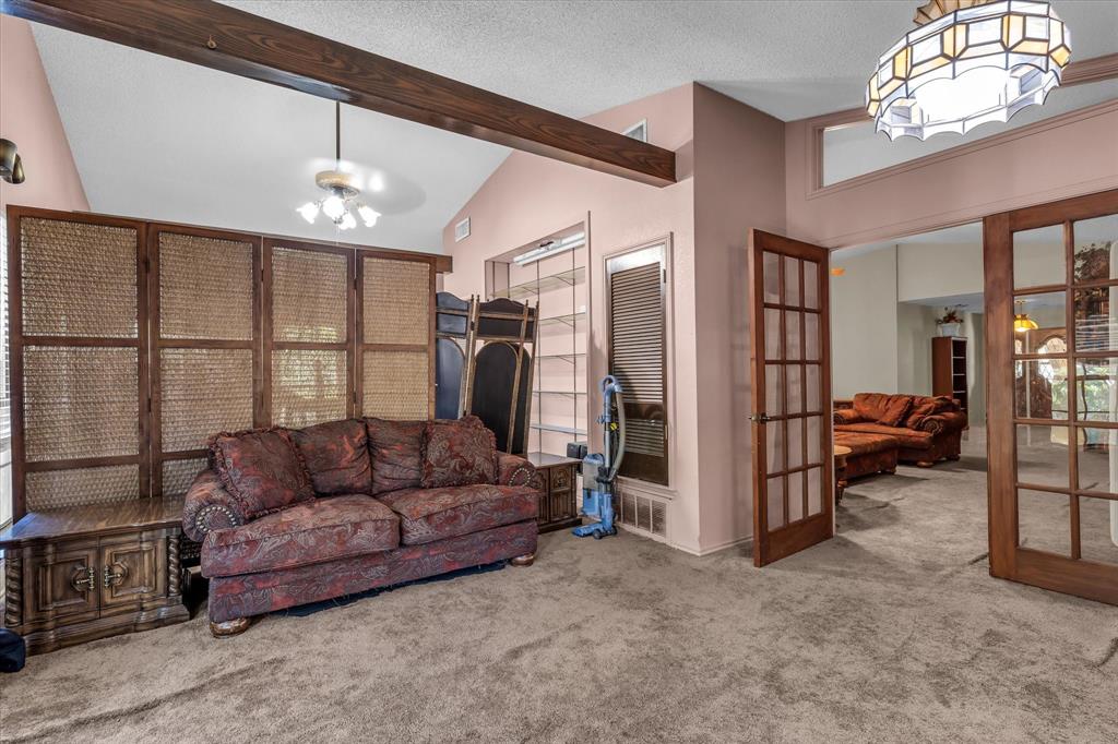 Vaulted ceiling with exposed wood beams, French doors with glass panels, and an overhead decorative light fixture