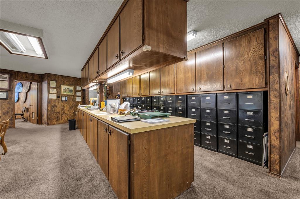 Extensive wood-finish cabinetry, integrated under-cabinet lighting, light-toned countertop, and recessed ceiling lighting